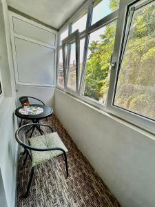 a small table and a chair in a room with windows at Elina apartament in Drobeta-Turnu Severin