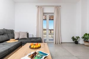 uma sala de estar com um sofá e uma mesa com uma taça de fruta em Marble Arch Apartments em Naxos Chora
