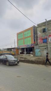 a man crossing the street in front of a building at Hotel Priyatama Residential in Dhaka