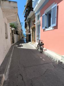 a bike parked on a street next to a pink building at ART House in Egina