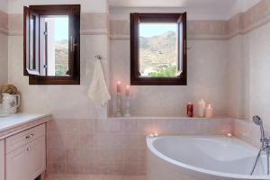 a bathroom with a tub and two windows with candles at Polixeni's House in Alinda +32 photos