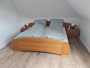ein Schlafzimmer mit einem Holzbett mit zwei Kissen in der Unterkunft Treeneperle in Schwabstedt