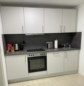 a kitchen with white cabinets and a stove top oven at Ferienwohnung Amstelbach - Nähe CHIO Aachen in Herzogenrath