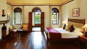a bedroom with a bed in a room with windows at Taj Kumarakom Resort and Spa Kerala in Kumarakom