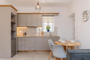 a kitchen with white cabinets and a table with chairs at Marble Arch Apartments in Naxos Chora
