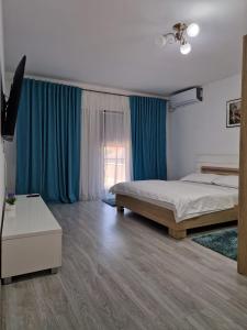 a bedroom with two beds and blue curtains at Villa Niko in Mamaia Nord