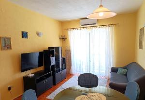 ein Wohnzimmer mit einem Sofa und einem TV in der Unterkunft Apartment near beach with free parking in Kaštela