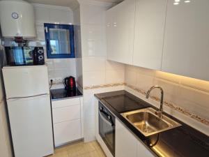 a white kitchen with a sink and a refrigerator at Apartment Bella Vista with sea view in Dehesa de Campoamor