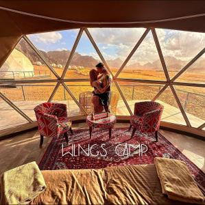 a couple kissing in front of a large window at WADI RUM WINGS lUXURY CAMP in Wadi Rum