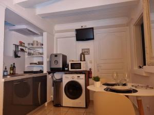 une cuisine avec une machine à laver et une table avec des chaises dans l'établissement Bienvenue à la Zolie Kaz !, à Saint-Pierre