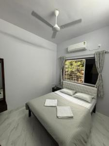 a bedroom with a bed with a ceiling fan and a window at White Haven Homestay in Alibag