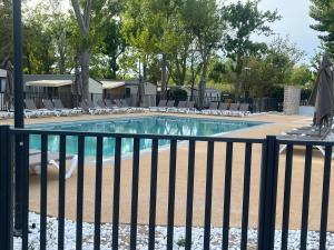 a swimming pool with chairs and a fence at Mobile home camping in Le Grau-du-Roi