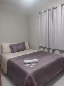 a bedroom with a large bed with purple sheets and curtains at Pousada e Alojamento Recanto São José hospedagem econômica em Rio Verde in Rio Verde