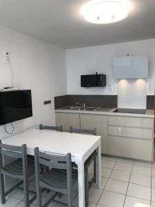 Trévou-TréguignecにあるRez de jardin 5 pers avec piscine, vue directe sur la plage à 40 mのキッチン(白いテーブル、椅子付)