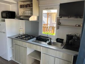 a kitchen with a sink and a stove and a window at Mobile home camping in Le Grau-du-Roi