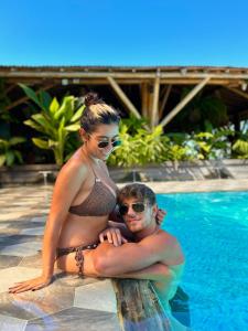 a man and a woman in a bikini sitting next to a swimming pool at La Veranda Hotel & Restaurant in Minca