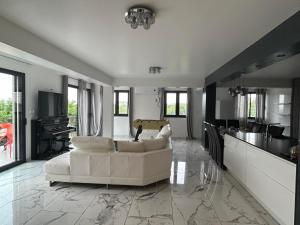 ein Wohnzimmer mit einem weißen Sofa und einer Küche in der Unterkunft Magnifique Villa avec piscine Beaujolais in Gleizé