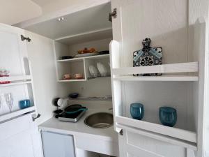 una pequeña cocina con armarios blancos y platos azules en Casa Livia en Castellabate