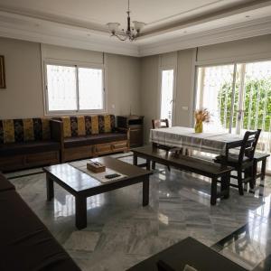 Villa Sérénité, Yasmine Hammamet في الحمامات: غرفة معيشة مع كنب وطاولة وكراسي