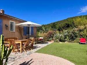 eine Terrasse mit Tisch und Stühlen und einem Sonnenschirm in der Unterkunft Villa Alexandra in La Croix-Valmer