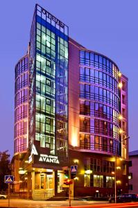 un grand bâtiment en verre avec un panneau devant lui dans l'établissement AVANTA hotel-center, à Novossibirsk