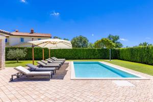 a swimming pool with lounge chairs and an umbrella at Villa Dionis in Kaštelir