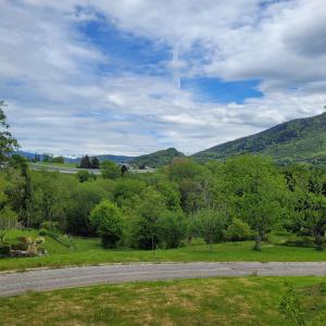 a road in a field with mountains in the background at Maison au calme, proche Chambéry in Vimines
