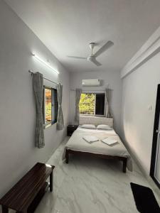 - une chambre avec un lit et un banc dans l'établissement White Haven Homestay, à Alībāg
