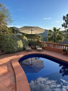 einen Pool mit einem Sonnenschirm, 2 Stühlen und einem Tisch in der Unterkunft Villa Caprice in Lloret de Mar