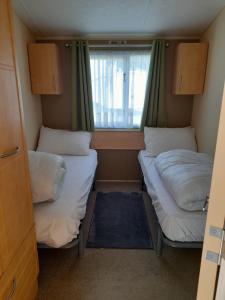 two beds in a small room with a window at Blancos by the sea in Saint Osyth
