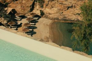 a pool of water with a beach and rocks at The Wild by Interni in Kalafatis