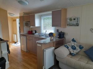 eine Küche mit einem Sofa und einem Tisch in einem Zimmer in der Unterkunft Blancos by the sea in Saint Osyth