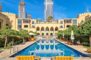 ein Hotel mit einem Pool vor einem Gebäude in der Unterkunft Burj khalifa partial view Peak living luxury 2BR Souk AL-Bahar Beside Dubai mall-GOLDEN HOMES in Dubai