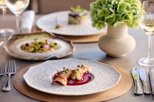 Pomegranate Wellness Spa Hotel في نيا بوتيدايا: طاولة مع أطباق من الطعام و مزهرية مع الزهور