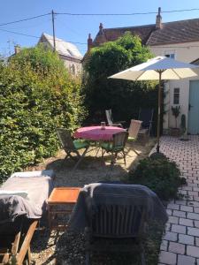 a patio with a table and an umbrella and chairs at Le Cabanon in Cosne Cours sur Loire