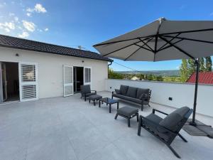 a patio with four chairs and an umbrella at Villa Anna's heaven in Imotski
