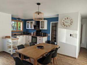 une cuisine avec une table et une horloge au mur dans l'établissement Jolie maison landaise tout confort, à Lugos