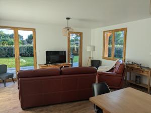 un salon avec un canapé et une télévision dans l'établissement Jolie maison landaise tout confort, à Lugos