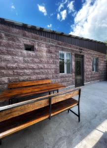 Lidiani Guest House في غيومري: كرسي خشبي جالس أمام مبنى من الطوب