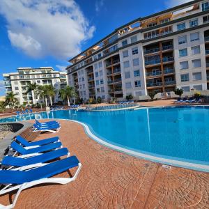 uma piscina com espreguiçadeiras em frente a um hotel em Sunny Suite em San Miguel de Abona