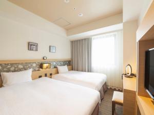 a hotel room with two beds and a television at Hotel Keihan Yodoyabashi in Osaka