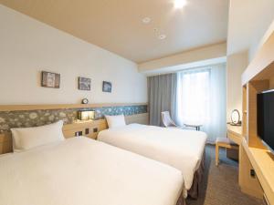 a hotel room with two beds and a flat screen tv at Hotel Keihan Yodoyabashi in Osaka
