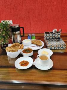 a table with plates of food and cups of coffee at Hotel King Plaza in New Delhi