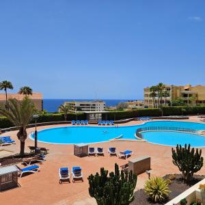 a large swimming pool with chaise lounges and chairs at Sunny Suite in San Miguel de Abona