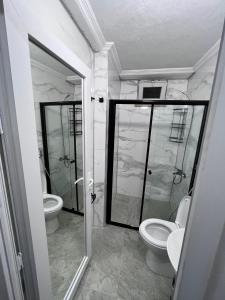 ein Badezimmer mit 2 WCs und einer Glasdusche in der Unterkunft YALI Apart Hotel in Trabzon