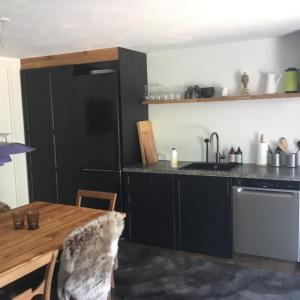 eine Küche mit einem schwarzen Kühlschrank und einem Tisch in der Unterkunft Marielyst B&B - Apartments in Næstved