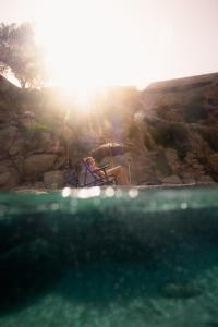 a person sitting in a chair next to the water at The Wild by Interni in Kalafatis