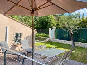 a patio with a table and chairs and an umbrella at Logement calme et chaleureux dans villa in Évenos