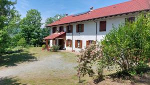 a large white house with a red roof at Cascina della Chiesa in Ponzone