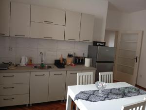 a kitchen with white cabinets and a table and a refrigerator at Apartman Radanović in Foča